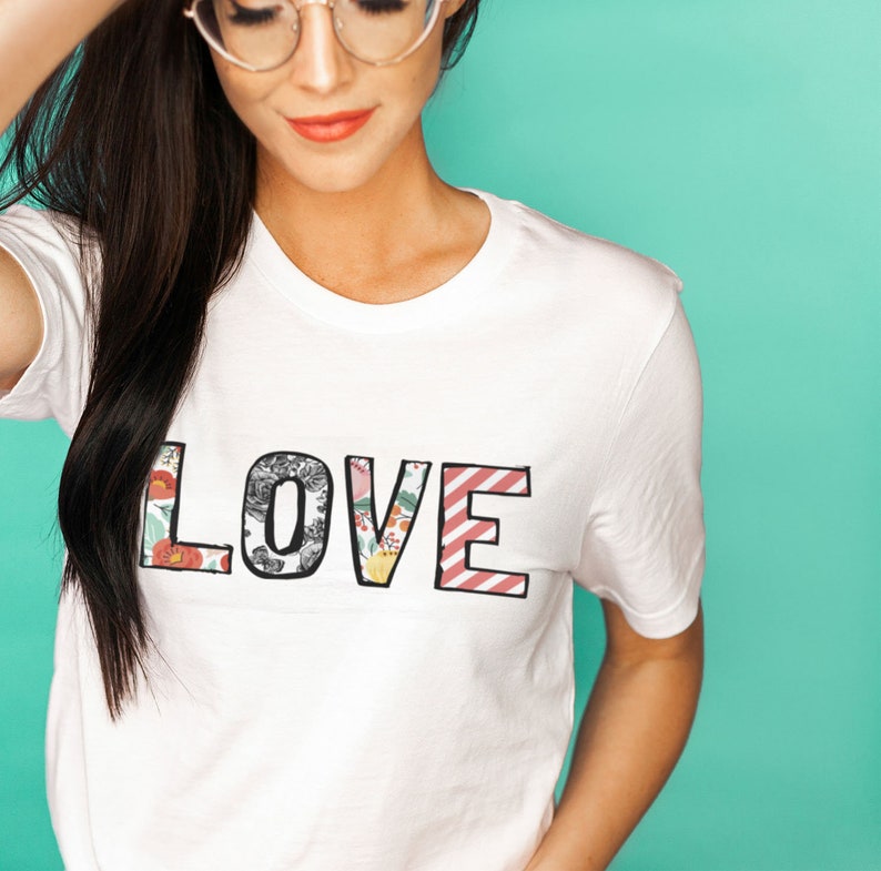 May include: White t-shirt with the word "LOVE" printed in large, colorful letters. The letters are made up of different floral patterns.