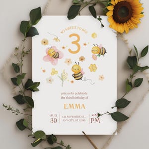 May include: A cream-colored birthday invitation with bee and flower illustrations. The text reads "So Sweet to Bee" and "join us to celebrate the third birthday of EMMA" with date, time, and address details. The invitation is surrounded by greenery and a sunflower.
