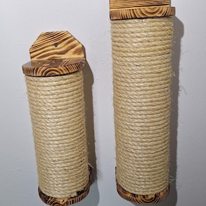 以下が含まれることがあります： 2つの猫用爪とぎ。各ポストは、自然色のロープで包まれた円柱です。ポストには木製の天板と底板があり、壁に取り付けられています。木材は濃い焦げ付き仕上げです。