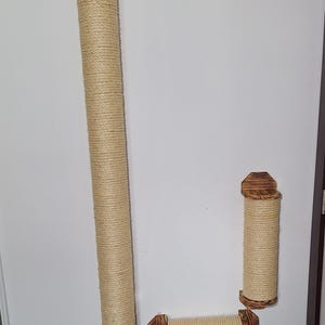 May include: A set of three cat scratching posts. The posts are wrapped in natural-coloured sisal rope and have wooden end caps. The posts are different sizes, with one tall post and two shorter posts.