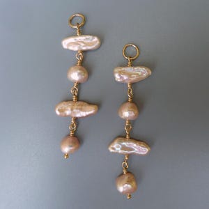 Puede incluir: Un par de pendientes largos y colgantes con múltiples perlas barrocas rosadas y detalles dorados.