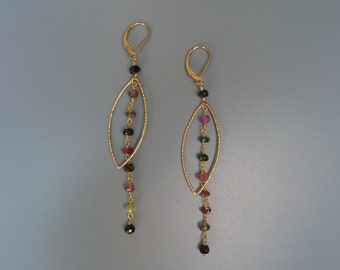 May include: Gold earrings with a dangling chain of multi-colored gemstones. The gemstones are black, pink, green, and brown.