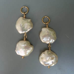 Puede incluir: Un par de pendientes de oro con dos perlas barrocas blancas en cada pendiente.