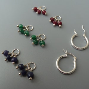 May include: Three pairs of dangle earrings with three gemstone beads each. The earrings are silver and feature red, green, and blue gemstones.