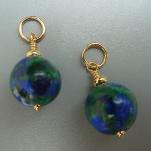 May include: Two gold-colored earrings with round, blue and green stone beads. Each earring has a small gold loop at the top and a gold bead at the bottom. The beads have a marbled appearance.
