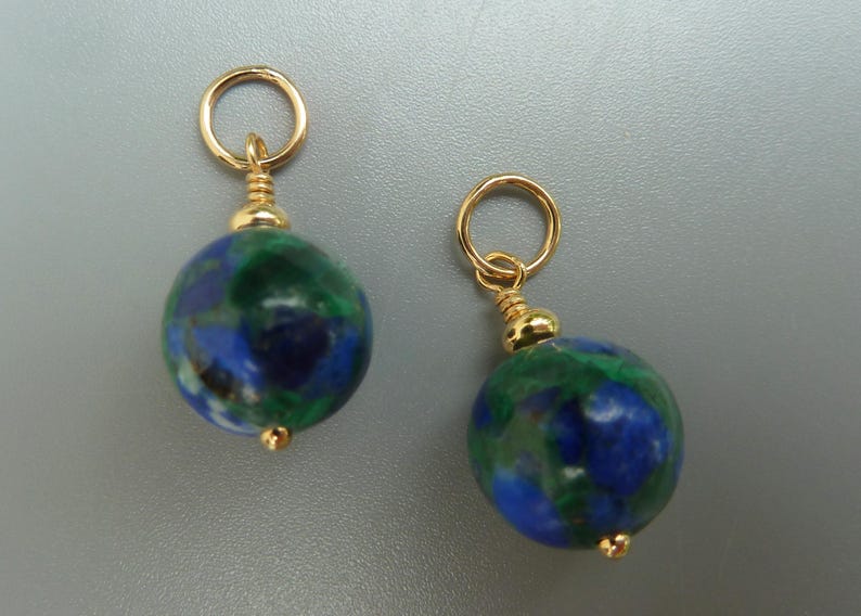 May include: Two gold-colored earrings with round, blue and green stone beads. Each earring has a small gold loop at the top and a gold bead at the bottom. The beads have a marbled appearance.