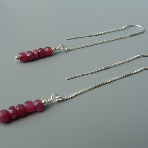 May include: A pair of silver dangle earrings with a row of pink gemstone beads.