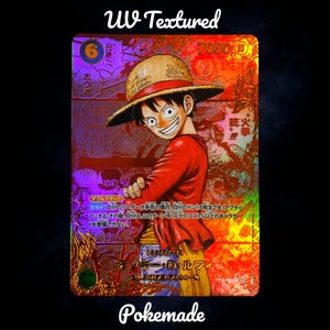 Può includere: Una carta collezionabile olografica con un personaggio dei cartoni animati sorridente con una camicia rossa e un cappello di paglia. La carta ha testo giapponese e le parole "UV Textured" e "Pokemade". Sfondo olografico oro e rosso.