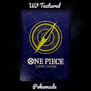 K&ouml;nnte beinhalten: Eine marineblaue One Piece-Spielkarte mit einem gelben Kompass-Design. Die Karte tr&auml;gt den Text "ONE PIECE CARD GAME", "UV Textured" und "Pokemade".