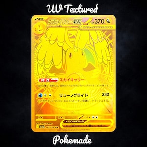 May include: A gold-coloured trading card with Japanese text and a dragon illustration. The card features the text "UV Textured" at the top and "Pokemade" at the bottom. The card has a holographic design.