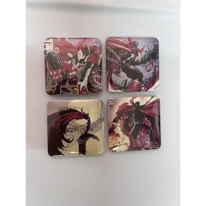 May include: Set of four square coasters featuring comic book art of the character Spawn. Each coaster displays a different action scene with Spawn in a red cape, set against a dark background. The coasters have a glossy finish.