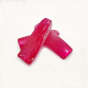 Pode incluir: Três gemas brutas de cor rosa, facetadas. As gemas são translúcidas e têm um brilho ligeiro.