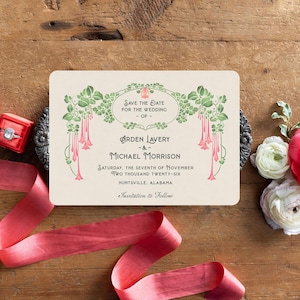 K&ouml;nnte beinhalten: Eine cremefarbene Hochzeitseinladung mit floralem und botanischem Design. Der Text lautet "Save the Date" und enth&auml;lt Namen, Datum und Ort. Das Bild enth&auml;lt auch ein rotes Band, Blumen und eine Ringbox.