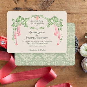K&ouml;nnte beinhalten: Eine Hochzeitseinladung mit floralem Design, mit den Namen "Arden Lavery" und "Michael Morrison" und dem Datum "Samstag, der siebte November zweitausendsechsundzwanzig." Die Einladung liegt auf einer Holzoberfl&auml;che mit Blumen und einem roten Band.