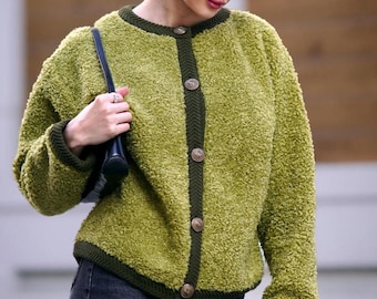 Puede incluir: Cárdigan verde texturizado con ribete y botones verde oscuro. Se combina con vaqueros negros. El conjunto se completa con gafas de sol y un bolso negro. La textura del cárdigan añade un elemento único.