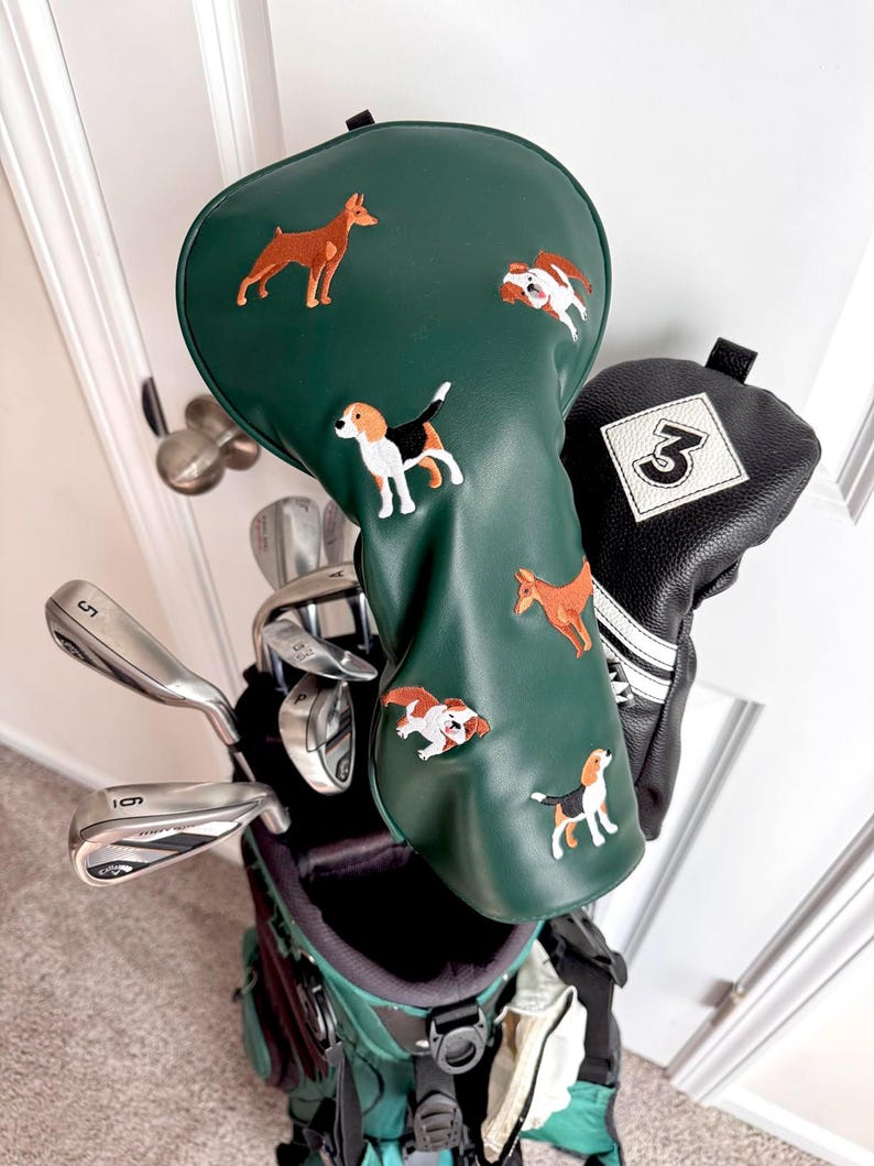 Puede incluir: Una bolsa de palos de golf con una funda verde para la cabeza con dise&ntilde;os de perros bordados. La bolsa incluye varios palos de golf y una funda negra con el n&uacute;mero 3 blanco.