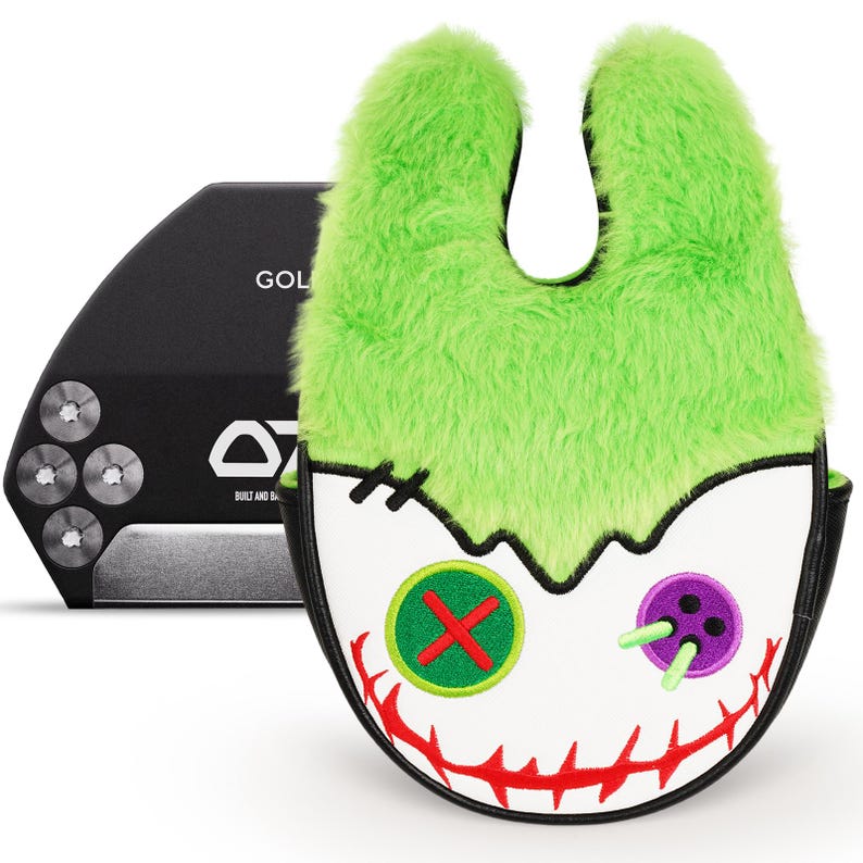 Pode incluir: Uma capa para a cabe&ccedil;a do taco de golfe com um design de rosto de monstro. A capa tem um topo verde peludo, um rosto branco e um rosto costurado com uma boca vermelha, olhos de bot&atilde;o verdes e roxos. Um taco de golfe preto est&aacute; no fundo.