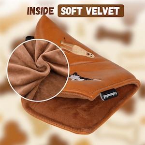 Puede incluir: Una funda para la cabeza del palo de golf marr&oacute;n con un interior de terciopelo suave. La funda presenta im&aacute;genes bordadas de un perro y un suricato. El texto "INSIDE SOFT VELVET" se muestra en la parte superior.
