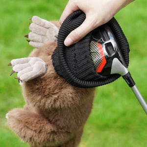 Puede incluir: Una funda para la cabeza del palo de golf de felpa marr&oacute;n con forma de topo, con una parte superior negra de punto tipo gorro. La funda tiene patas de color marr&oacute;n claro con garras. Un palo de golf est&aacute; parcialmente insertado en la funda.
