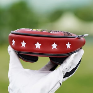 Peut inclure: Un prot&egrave;ge-t&ecirc;te de club de golf rouge avec des &eacute;toiles blanches brod&eacute;es et une bordure noire. Le prot&egrave;ge-t&ecirc;te pr&eacute;sente un motif d'aigle et est tenu par une main gant&eacute;e. Il est con&ccedil;u pour prot&eacute;ger la t&ecirc;te du club de golf.