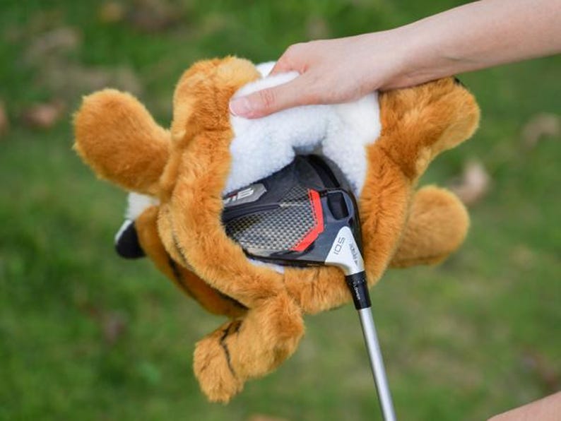 Puede incluir: Una funda para la cabeza del palo de golf con forma de zorro, en tonos marr&oacute;n y blanco, con un palo de golf parcialmente insertado. La funda tiene una textura de felpa y est&aacute; dise&ntilde;ada para proteger la cabeza del palo.