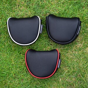 Może przedstawiać: Trzy czarne osłony na głowę puttera golfowego z białymi i czerwonymi wykończeniami, na zielonej trawie. Każda osłona ma napis "Craftsman Golf" wydrukowany z boku.