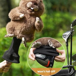 Puede incluir: Una funda para la cabeza del palo de golf de felpa marr&oacute;n con forma de castor. La funda tiene un calcet&iacute;n de punto negro y est&aacute; dise&ntilde;ada para encajar sobre un palo de golf. El texto "Won't Fall Off" es visible.