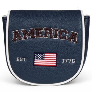 May include: A navy blue mallet putter headcover with a textured leather-like finish and white piping. The word AMERICA is embroidered in dark brown with white outlines. Below, an embroidered American flag sits between the text EST and 1776.