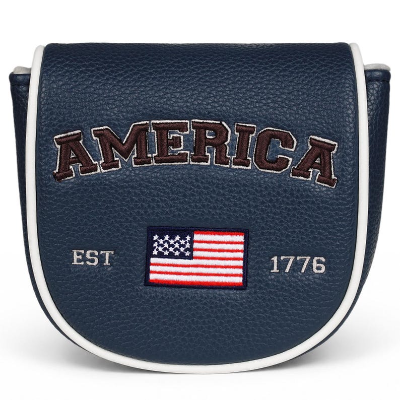 May include: A navy blue mallet putter headcover with a textured leather-like finish and white piping. The word AMERICA is embroidered in dark brown with white outlines. Below, an embroidered American flag sits between the text EST and 1776.