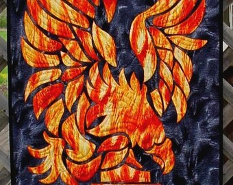 May include: A fiery orange and yellow phoenix with outstretched wings against a dark blue background. The phoenix is a mythical bird that symbolizes rebirth and renewal.