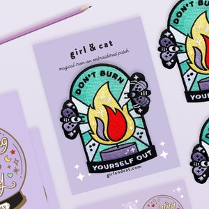 以下が含まれることがあります： 炎と「Don't Burn Yourself Out」というテキスト、そして「girlandcat.com」というウェブサイトが書かれた、ターコイズブルーとパープルの刺繍入りアイロン接着パッチです。