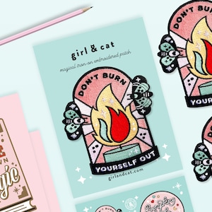 Pu&ograve; includere: Tre toppe ricamate da stirare con uno schema di colori rosa e giallo. Le toppe presentano una fiamma con il testo "Don't Burn Yourself Out" e una falena con un occhio. Sono anche visibili il testo "girl & cat" e il sito web "girlandcat.com".