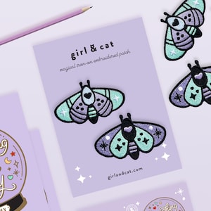 May include: Four iron-on embroidered patches featuring a moth design with purple, green, and white accents. The patches are on a purple background with white stars. The text "girl & cat" and "girlandcat.com" are also visible.