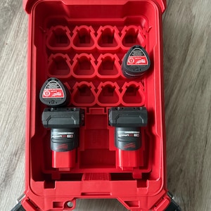 May include: Red tool box with a clear lid, containing multiple black and red batteries. The batteries are labeled "Milwaukee REDLITHIUM".