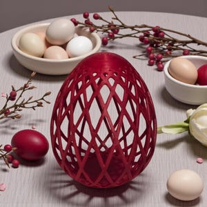 May include: A red, lattice-design egg-shaped decorative object. The object is surrounded by white bowls filled with eggs of various colours, red eggs, and sprigs of berries. The egg-shaped object has a diamond-shaped pattern throughout its design.