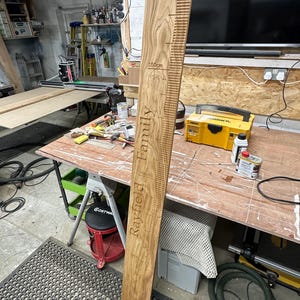 Op de afbeelding: Een houten groeimeter met de woorden "Rayfield Family" en metingen in centimeters tot 150 cm.