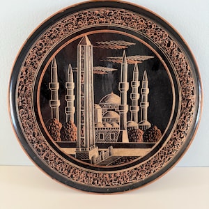 Turkish etched copper plate 7.5 inches in diameter with hook attached for hanging. Good condition. Some minor wear.