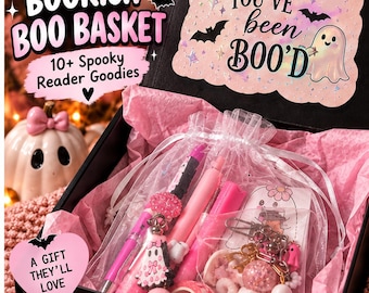 May include: A black gift box containing pink tissue paper and various items including pens, a small ghost-shaped charm, and decorative tape. The box lid features text reading BOOKISH BOO BASKET 10+ Spooky Reader Goodies and YOU'VE been BOO'D.