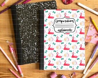 May include: A composition notebook with a flamingo pattern, featuring pink flamingos, beach balls, and bows on a white background. The notebook is next to a black and white composition notebook, with pink and purple pens and pencils scattered around.