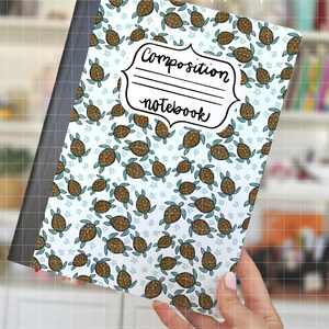 Puede incluir: Cuaderno de composición con un patrón de tortugas marinas marrones y pequeñas flores azules sobre un fondo blanco. El cuaderno tiene una espina negra y las palabras "Composition notebook" en una etiqueta decorativa.