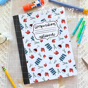 May include: A composition notebook with a white cover featuring a pattern of red wine glasses, strawberries, and blue accents. The notebook has a black spine and the words "Composition Notebook" on the cover.