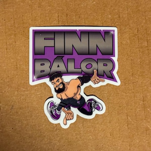 May include: A purple and silver sticker with the text "FINN BÁLOR" and a cartoon image of a wrestler in a black and purple outfit.