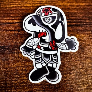 May include: A sticker featuring a stylized cartoon dog with a black and white design, accented with red flames and details. The dog is depicted in a standing pose, with a bold, graphic style reminiscent of tattoo art.