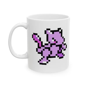 May include: White ceramic mug featuring a pixelated image of a purple Mewtwo character. The design is in shades of purple and black, with a retro video game aesthetic. The mug has a curved handle.