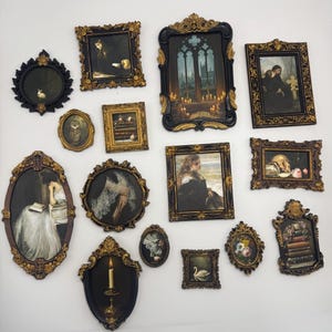 May include: A collection of thirteen wall-mounted picture frames in various shapes and sizes, featuring ornate gold and black detailing. The frames contain diverse artworks including portraits, landscapes, still lifes, and scenes with animals and candles.