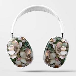 May include: White wireless headphones with a floral design featuring white flowers, green leaves, and gold accents.