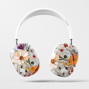 May include: White wireless headphones with a floral pattern on the earcups. The pattern features white, orange, and pink flowers on a white background.