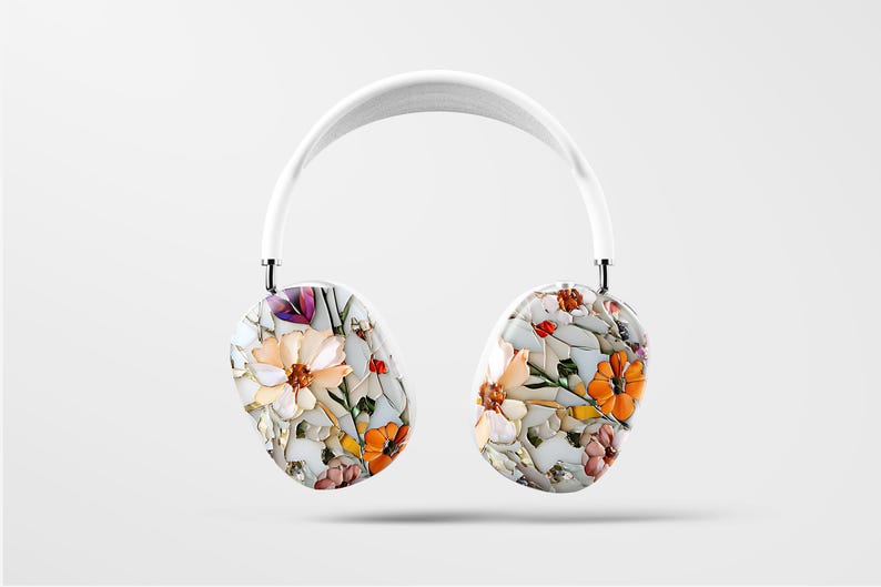 May include: White wireless headphones with a floral print featuring white, orange, and pink flowers. The headphones have a white headband and white earcups.