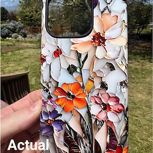 May include: A white phone case with a colorful floral design. The flowers are orange, pink, purple, and white. The case has a cutout for the camera lens.