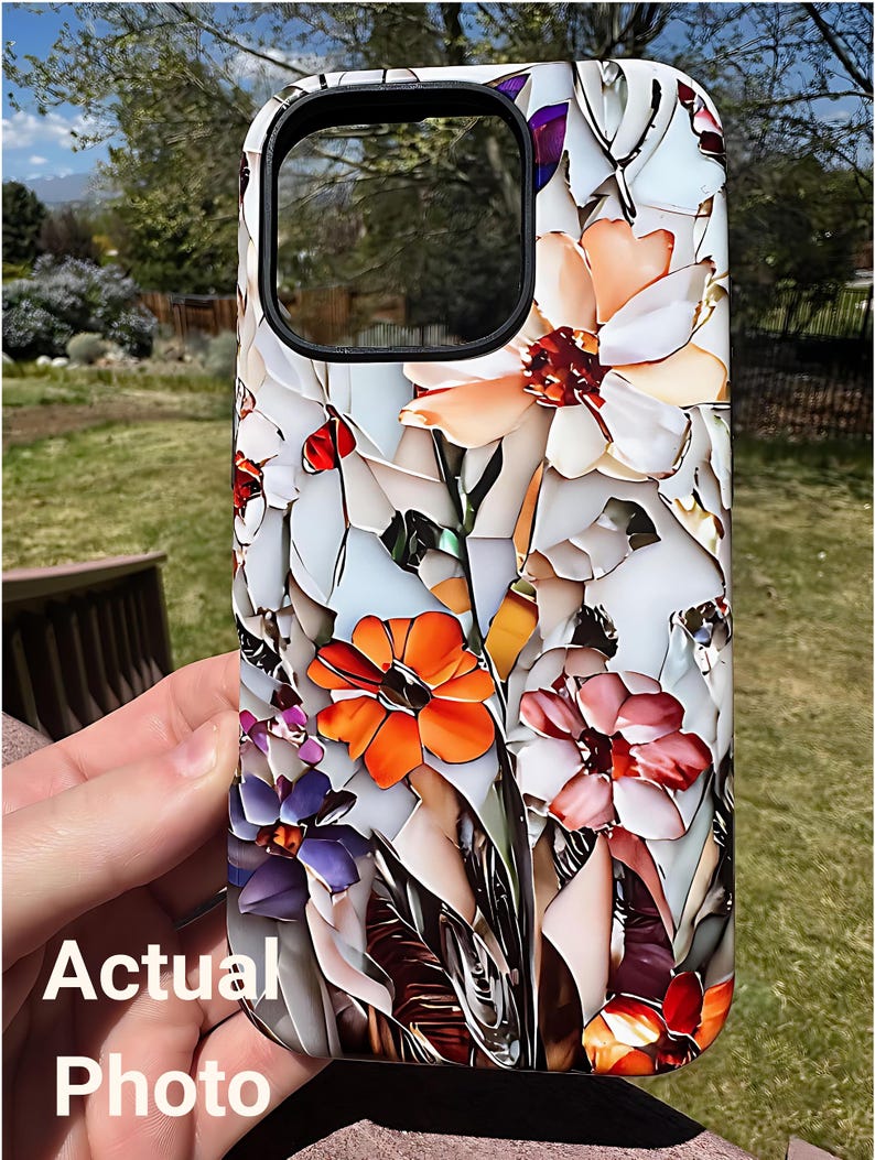 May include: A white phone case with a colorful floral design. The flowers are orange, pink, purple, and white. The case has a cutout for the camera lens.